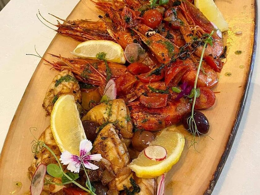 Oval platter of grilled prawns, octopus and white fish with lemon, olives and tomatoes