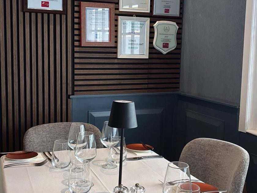 Set white table in front of a wood-slat wall covered in restaurant award certificates